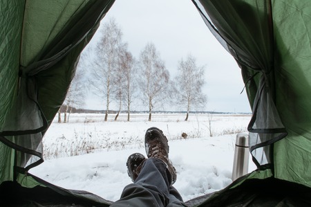 View from the inside of the tent, broken into the winter. The traveler relaxes in a halt. The legs of the tentの写真素材