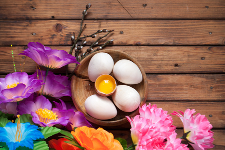 Easter eggs and flowers on wooden boards, artificial flowers and decorative eggs from wood, Easter backgroundの写真素材