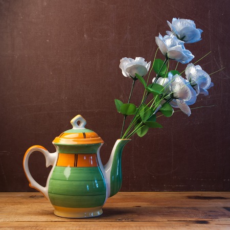 Artificial roses in a creative vase, flowers in a teapot, concept the arrival of springの写真素材