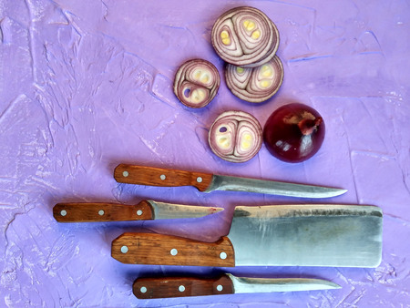 Onion is whole and sliced. Chopped onions on a cutting Board. Knives with a wooden handle. Cooking dishes with onions. vegetables for a healthy diet.の写真素材