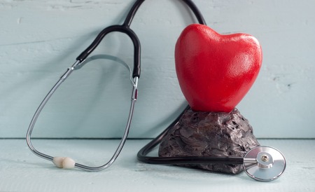 close - up of red heart and stethoscope on blue background, world health day concept, wooden tableの写真素材
