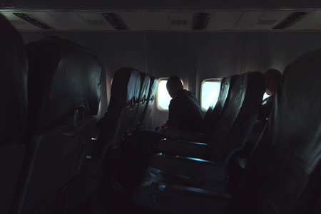 The passenger looks out the window, bright light in the Windows of the aircraft. photo in low keyの写真素材