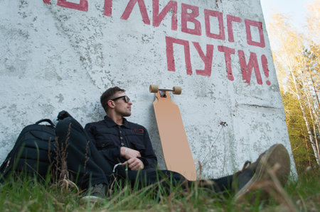 The guy is sitting next to the longboard, the concept of traveling on the longboard, the inscription...