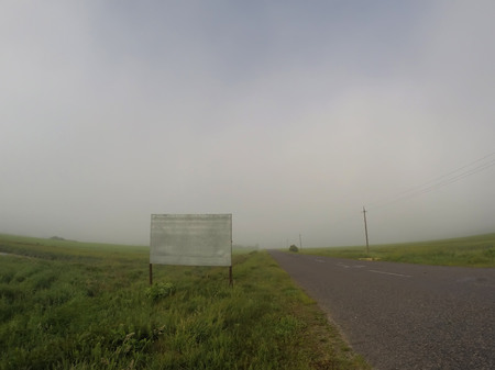 Billboard in the fog, the road along the field,の写真素材