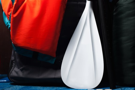 SUP Board in case, orange life jacket and white paddle close-up, sports equipment for river raftingの写真素材