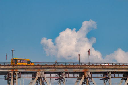 Yellow bus rides on the bridge, school bus on the sky background