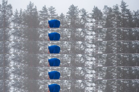 closeup of a teenager, standing in the blue sweatshirt holding the hand of a skateboard on the background of a winter forest, a lost skater,の写真素材
