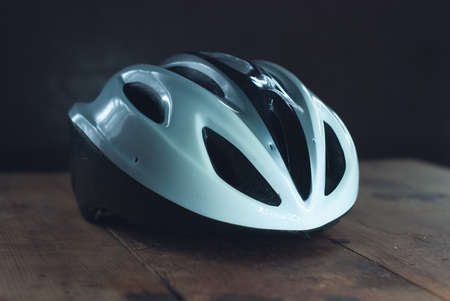 Bicycle helmet on wooden table, white plastic helmet on dark background, protection for cyclist,の写真素材