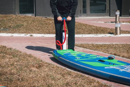 Sports man inflates pump paddle Board, fashionable modern entertainment