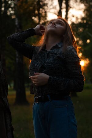 A young country girl, enjoying time in the Park with the sunset in the background.の写真素材