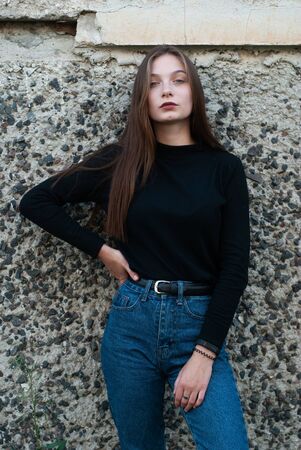 Beautiful slender girl in blue jeans posing at the concrete wall,の写真素材