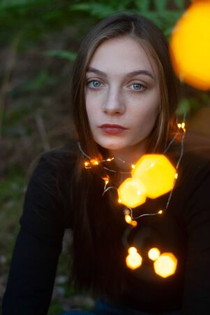 A young girl holding a yellow garland in her hands, a Portrait of a garland close-upの写真素材
