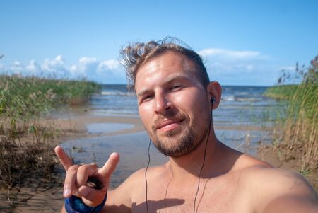 Funny guy takes selfie on Ladoga lake beach,の写真素材