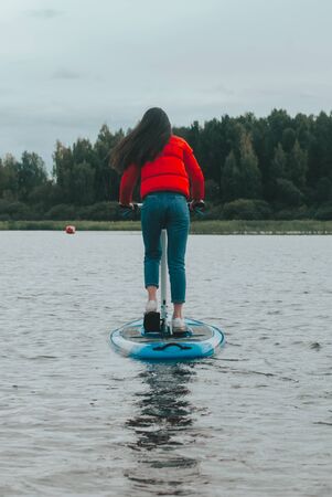 Girl in a red jacket floating on the whimsical pedal Boardの写真素材
