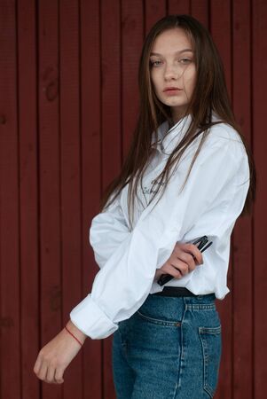 A girl posing against a red background, a young model in a white shirt and with long straight hair,の写真素材