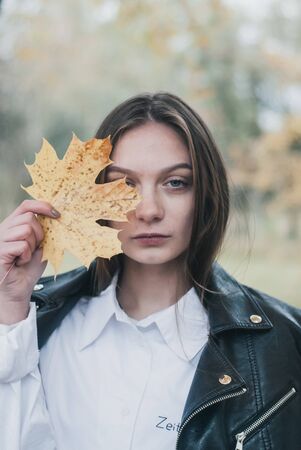 young woman holding gold leaf tree outdoors in forest,の写真素材