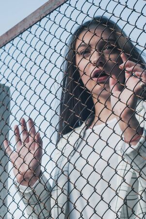 Girl holding hand on metal chain wire mesh, concept of abuse of women human trafficking, crime and domestic violence,の写真素材