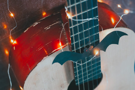 Acoustic guitar in autumn season. guitar with garland and bat. Concept sale of guitars on Halloween...