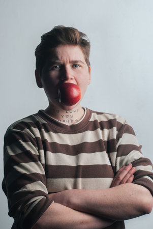 A young saucy girl holds a red Apple in her mouth. Girl fruit eater. Prevention of spring beriberi.