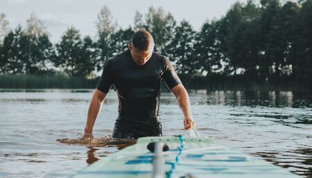 SUP Board and paddle closeup, surfer comes out of the water like a super heroの写真素材