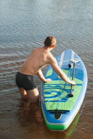 Slim guy on the sup Board. the view from the back,の写真素材