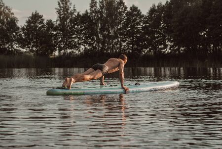 A young guy makes a plank on a sup Board. SUP yoga,の写真素材