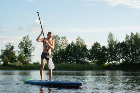 Guy doing paddle boarding on lake, lucky man on SUP Board,の写真素材