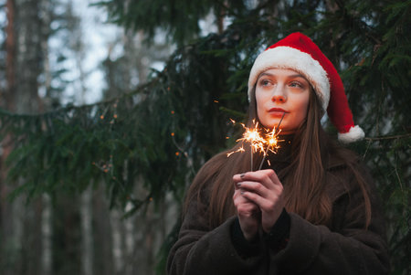 Beautiful happy young girl with Santa Claus hat. Holding sparklers.