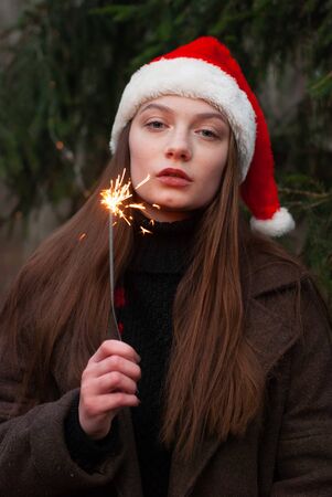 Beautiful happy young girl with Santa Claus hat. Holding sparklersの写真素材