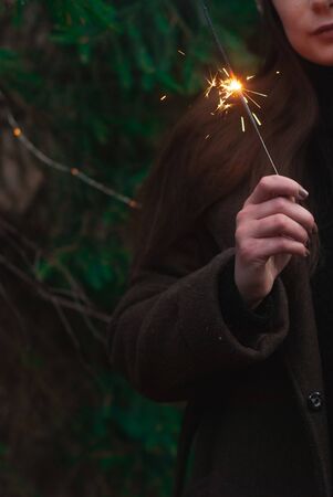 A womans hand holds a Sparkler on a forest background,の写真素材