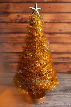 Yellow Christmas tree with a star on a wooden background. Artificial Christmas tree and bokeh,の写真素材