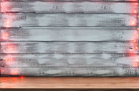 an empty table in front of a Christmas red garland of lights on a wooden rustic backgroundの写真素材