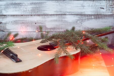 Acoustic guitar with garland and fir branch on wooden background, Christmas giftの写真素材