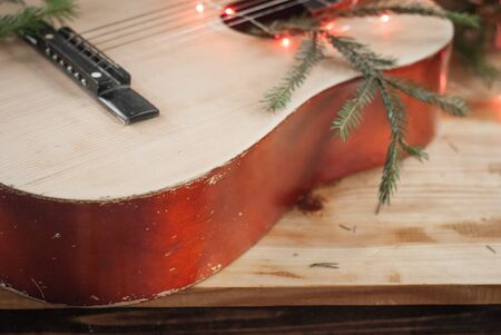 Old acoustic guitar with garland on wooden background, Christmas guitar,の写真素材
