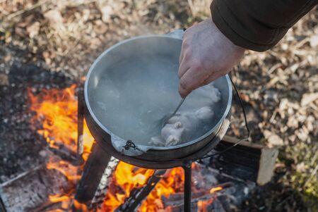 Pot on the fire top view, a mans hand stirs the boiling water in the pot,の写真素材