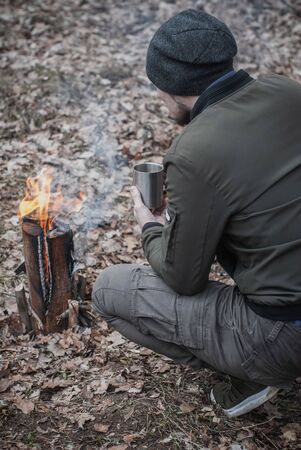 A man drinks tea from an iron mug and looks at the fire,の写真素材