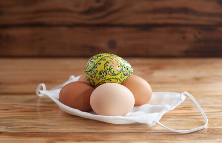 Easter eggs and a medical mask on a wooden tableの写真素材