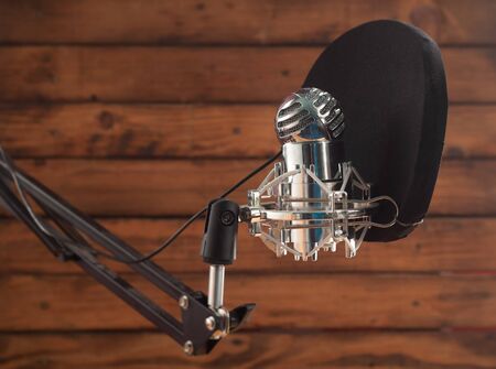 Condenser microphone and pop filter on a wooden background, room for recording podcastsの写真素材
