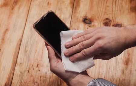 Mens hands wipe smartphone close-up, prevention covid-19,の写真素材