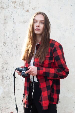 Cool hipster girl with a camera in her hands on a white backgroundの写真素材