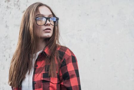 beautiful hipster girl in red shirt posing on white grunge wall backgroundの写真素材