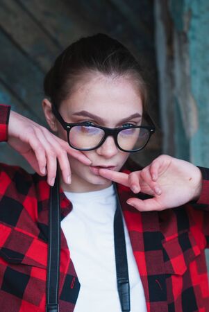 Hipster girl in glasses touches fingers of lips, portrait of a young girl,の写真素材