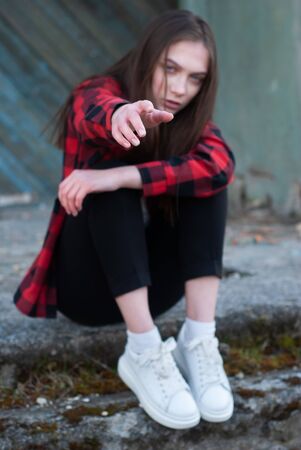 A lonely sad girl holds out her hand, asking for helpの写真素材