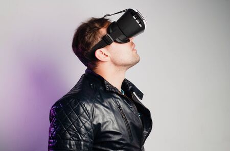 A man in VR glasses on a white background looks upの写真素材