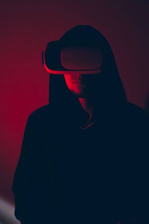 A hacker in the VR glasses in red light, the gamer in the virtual spaceの写真素材