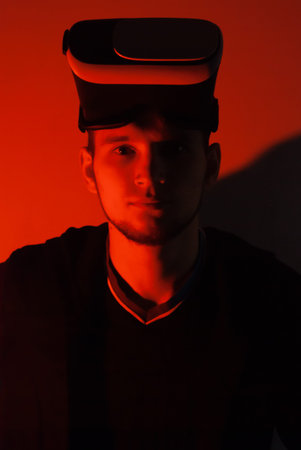 A hacker in the VR glasses in red light, the gamer in the virtual space,