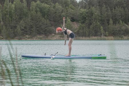 girl learns to stand on a Board with a paddle, balance trainingの写真素材