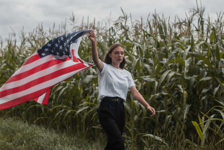 A girl with an American flag walks along a cornfield, labor Day,の写真素材