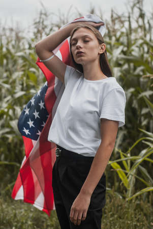 Girl with the usa flag on the background of high corn bushes, labor day concept,の写真素材