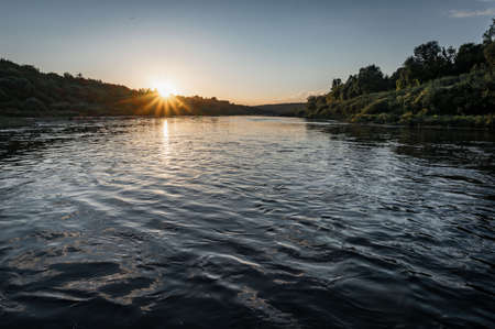 beautiful sunset on the river, the sun sets over the horizonの写真素材